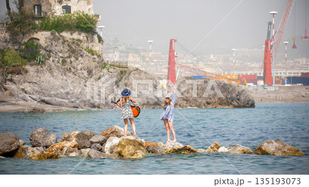 Women enjoying freedom on rocky beach with guitar Women enjoying freedom on rocky beach with guitar 135193073