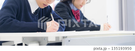学校や塾などで受験対策の模試のテストを受ける高校生の男女　顔無し 135193950