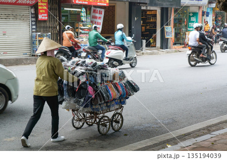 ベトナムの街中を手押し車を押しながら歩いている人 ベトナムの街中を手押し車を押しながら歩いている人 135194039