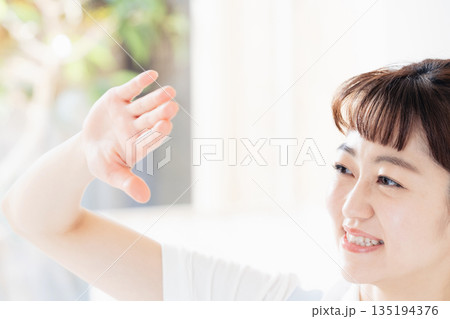 眩しそうに手をかざす介護士の女性 135194376