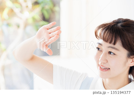眩しそうに手をかざす介護士の女性 135194377