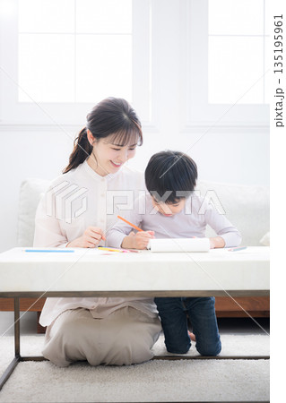 母親（ママ）に見守られながら、ノートを開いて学びを楽しむ幼児　お絵描きや塗り絵など一緒に楽しむ 135195961