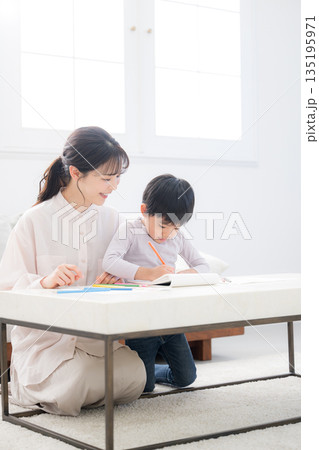 母親（ママ）に見守られながら、ノートを開いて学びを楽しむ幼児 135195971