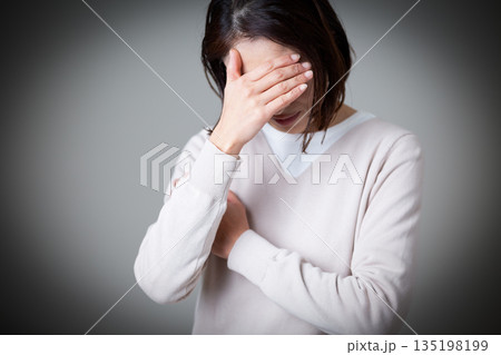 思い悩むカジュアルニット姿のミドル女性 135198199