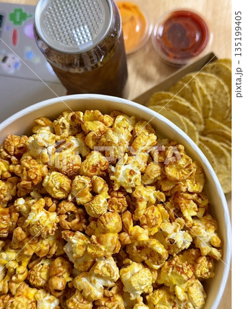 A bowl of freshly popped popcorn with a light buttery coating. A classic and satisfying snack, perfect for movie nights or casual gatherings. 135199405