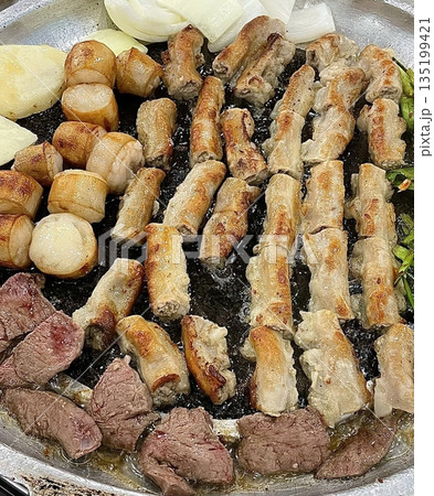 Grilled samgyeopsal, showcasing thick slices of pork belly sizzling on the grill. A popular Korean barbecue dish, capturing the essence of a delicious dining experience. 135199421