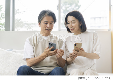 スマートフォンの画面を見る笑顔の50代の夫婦 135199664