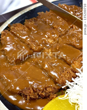 Crispy tonkatsu, a Japanese-style breaded and deep-fried pork cutlet, served with shredded cabbage and drizzled with savory sauce. A delightful balance of crunchy texture and juicy meat. 135200710