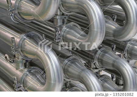 A lot of shiny curved stainless steel pipes of industrial equipment cooling system 135201082