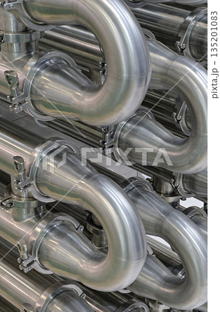 A lot of shiny curved stainless steel pipes of industrial equipment cooling system 135201083