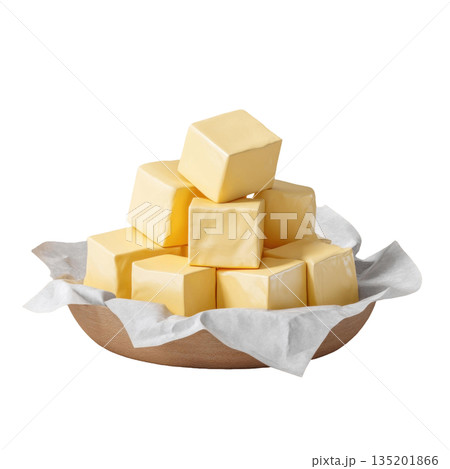 Butter cubes stacked in wooden bowl lined with white parchment paper, showcasing smooth, creamy texture and rich yellow color 135201866