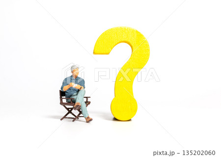 Miniature Man Sitting Beside Yellow Question Mark 135202060