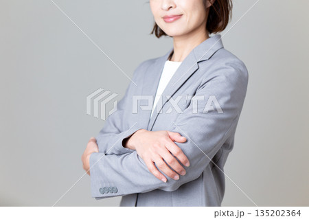 腕組みをするグレーのスーツを着たミドル女性ビジネスウーマン 腕組みをするグレーのスーツを着たミドル女性ビジネスウーマン 135202364