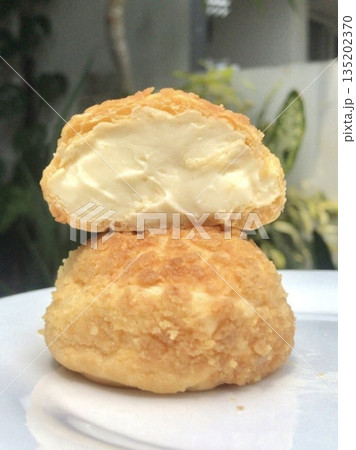 Golden choux au craquelin, featuring crisp pastry shells topped with a delicate, crumbly layer and filled with luscious cream. A delightful treat perfect for any indulgent moment. 135202370
