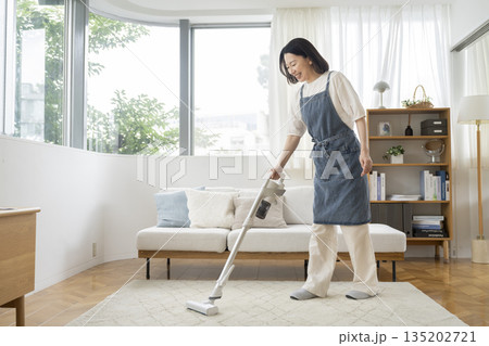 リビングルームで掃除機をかける50代の女性 135202721