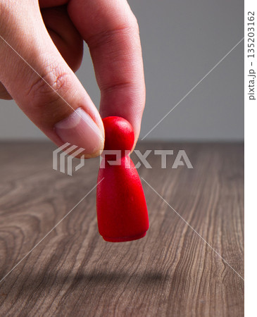 Hand moving red wooden game piece Hand moving red wooden game piece 135203162