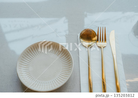 Modern Table Setting with Gold Cutlery and Ceramic Plate Modern Table Setting with Gold Cutlery and Ceramic Plate 135203812