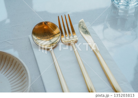 Modern Table Setting with Gold Cutlery and Ceramic Plate Modern Table Setting with Gold Cutlery and Ceramic Plate 135203813