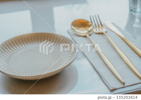 Modern Table Setting with Gold Cutlery and Ceramic Plate Modern Table Setting with Gold Cutlery and Ceramic Plate 135203814