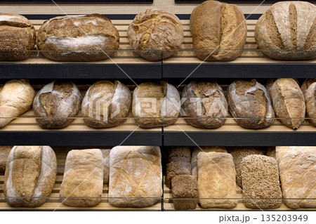 Various types of traditional homemade bread on the wooden shelves of a bakery store 135203949