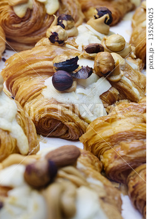 Group of fresh baked croissants, with topping of butter cream, caramel and roasted hazelnuts Group of fresh baked croissants, with topping of butter cream, caramel and roasted hazelnuts 135204025