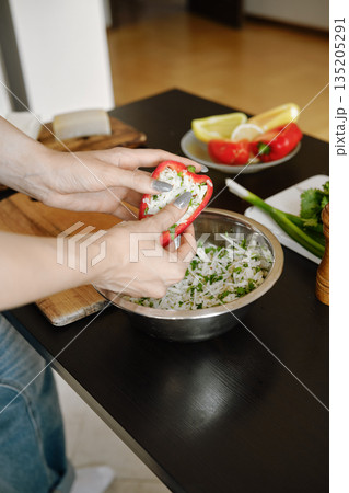 Female fingers pressing the filling into bell pepper 135205291