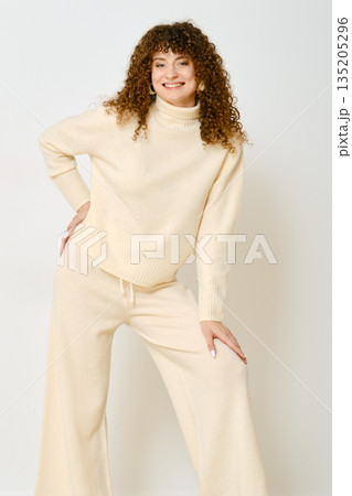 Cheerful woman in knitted sweater and wide-leg pants leaned forward with her hand on her knee Cheerful woman in knitted sweater and wide-leg pants leaned forward with her hand on her knee 135205296