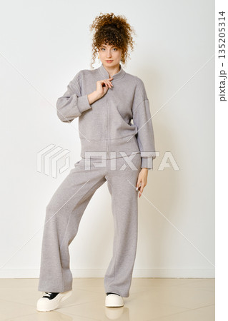 Woman in casual grey outfit poses confidently against a simple background 135205314