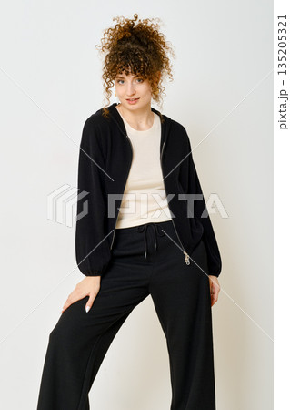Stylish model showcases casual outfit in modern indoor setting with simple background 135205321