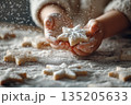 Childs hands holding a star-shaped cookie covered in powdered sugar. Christmas baking concept for holiday celebration. Winter dessert preparation. 135205633