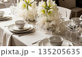 Elegant table setting with white amaryllis flowers and tableware, creating a festive atmosphere for a Christmas or holiday dinner arrangement. 135205635