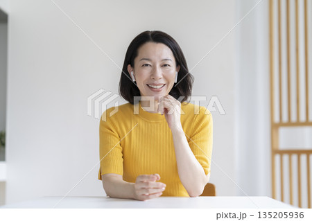 カメラ目線で話すイヤホンをつけた50代の女性 135205936