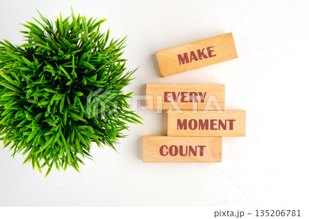 wooden blocks show the phrase make every moment count next to a bright green potted plant on a white surface, encouraging living a life full of purpose wooden blocks show the phrase make every moment count next to a bright green potted plant on a white surface, encouraging living a life full of purpose 135206781