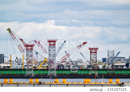 東京湾岸の工業地帯 立ち並ぶ建設用クレーンと曇天の空 東京湾岸の工業地帯 立ち並ぶ建設用クレーンと曇天の空 135207325