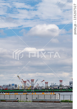 東京湾岸の工業地帯 立ち並ぶ建設用クレーンと曇天の空 東京湾岸の工業地帯 立ち並ぶ建設用クレーンと曇天の空 135207327
