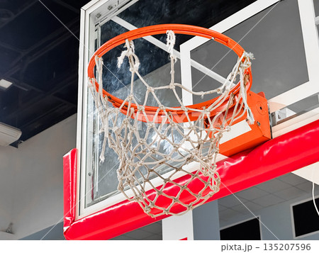 Basketball hoop with net in indoor sports facility. 135207596