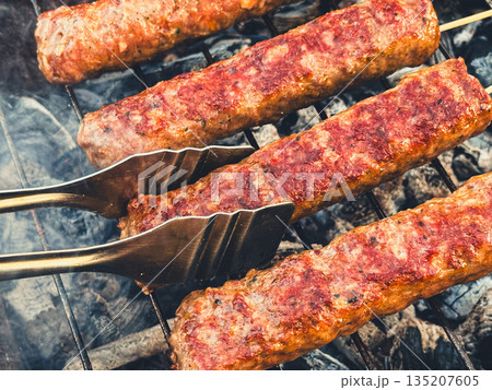 Delicious grilled kebabs sizzling on the barbecue grill. 135207605
