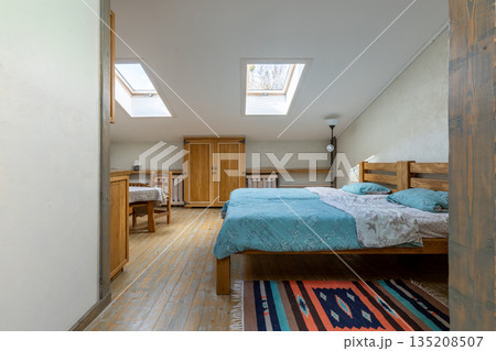 Bright rustic attic interior with twin beds and dining area Bright rustic attic interior with twin beds and dining area 135208507