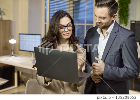 Coworkers Discuss Business Strategy on Laptop in Modern Office, Teamwork Concept Coworkers Discuss Business Strategy on Laptop in Modern Office, Teamwork Concept 135208652