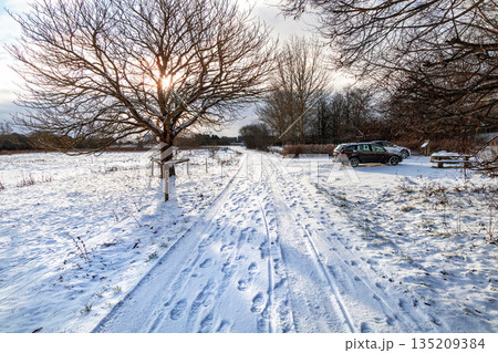 Country road with human footprints and parked cars under sunlight 135209384