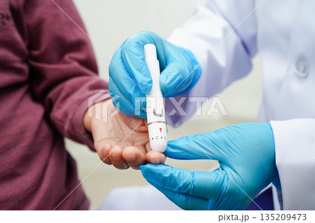 Asian senior woman using lancet pen on senior patient finger for check sample blood sugar level to treatment diabetes. 135209473