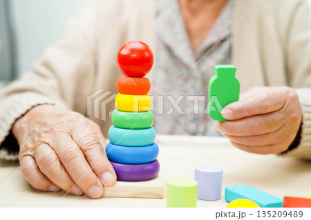 Asian elderly woman playing enhancing skill board game. 135209489