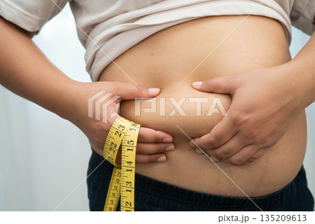 Asian woman use hand to squeeze fat belly big size overweight and obesity. 135209613