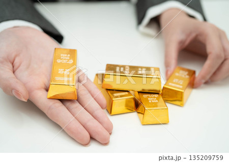 Asian woman holding gold bar in finance business. Asian woman holding gold bar in finance business. 135209759