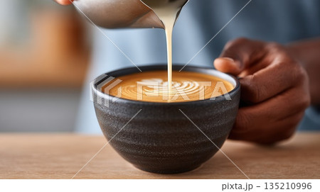 Barista pouring milk into coffee cup with latte art Barista pouring milk into coffee cup with latte art 135210996