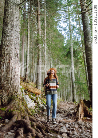 Woman with backpack hiking outdoors in the Forest. Trekking in the Pine Woods. Hiking lifestyle Woman with backpack hiking outdoors in the Forest. Trekking in the Pine Woods. Hiking lifestyle 135211209