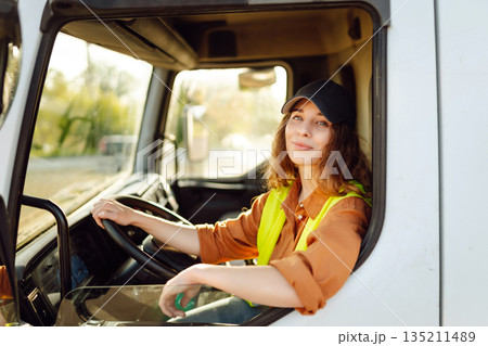 Portrait of beautiful young woman professional truck driver checking shipment list on a -parking lot Portrait of beautiful young woman professional truck driver checking shipment list on a -parking lot 135211489