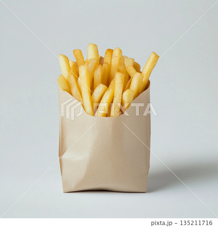 A brown paper bag filled with golden, crispy French fries is shown against a white background. 135211716