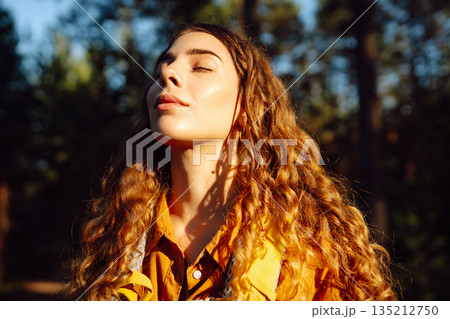 Tourist woman hiking alone in thick autumn forest. Stylish female looks for pathway among trees. Tourist woman hiking alone in thick autumn forest. Stylish female looks for pathway among trees. 135212750