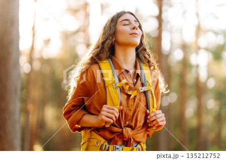 Tourist woman hiking alone in thick autumn forest. Stylish female looks for pathway among trees. 135212752